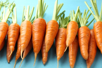 Tasty ripe juicy carrots on light blue wooden table, closeup