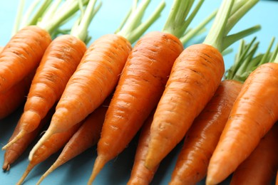 Tasty ripe juicy carrots on light blue table, closeup