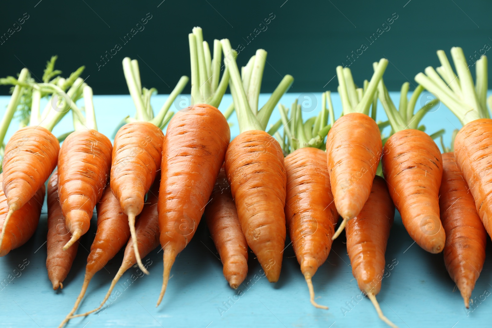 Photo of Tasty ripe juicy carrots on light blue wooden table, closeup