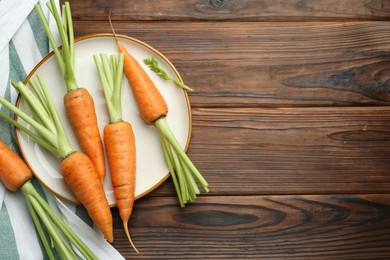 Photo of Tasty ripe juicy carrots on wooden table, top view. Space for text