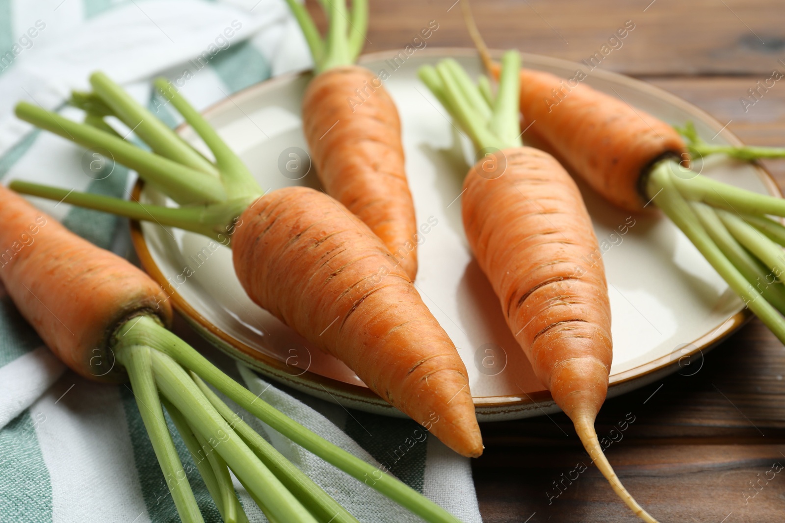 Photo of Tasty ripe juicy carrots on wooden table, closeup