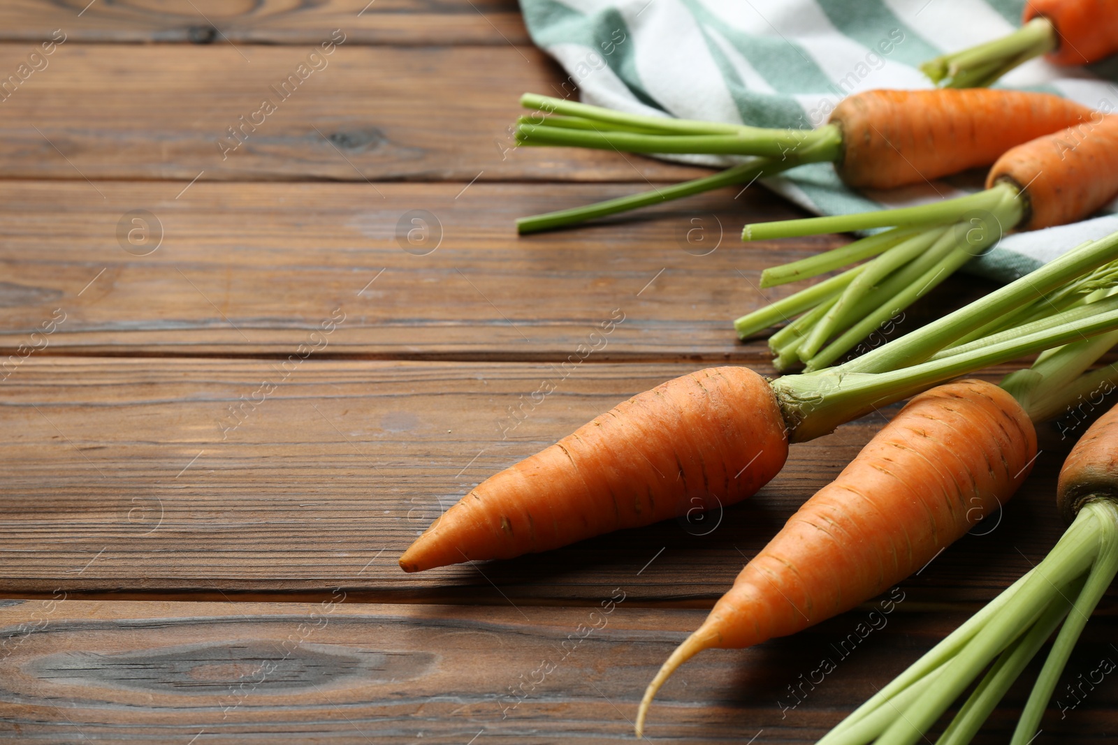 Photo of Tasty ripe juicy carrots on wooden table, closeup. Space for text