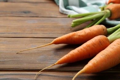 Photo of Tasty ripe juicy carrots on wooden table, closeup. Space for text