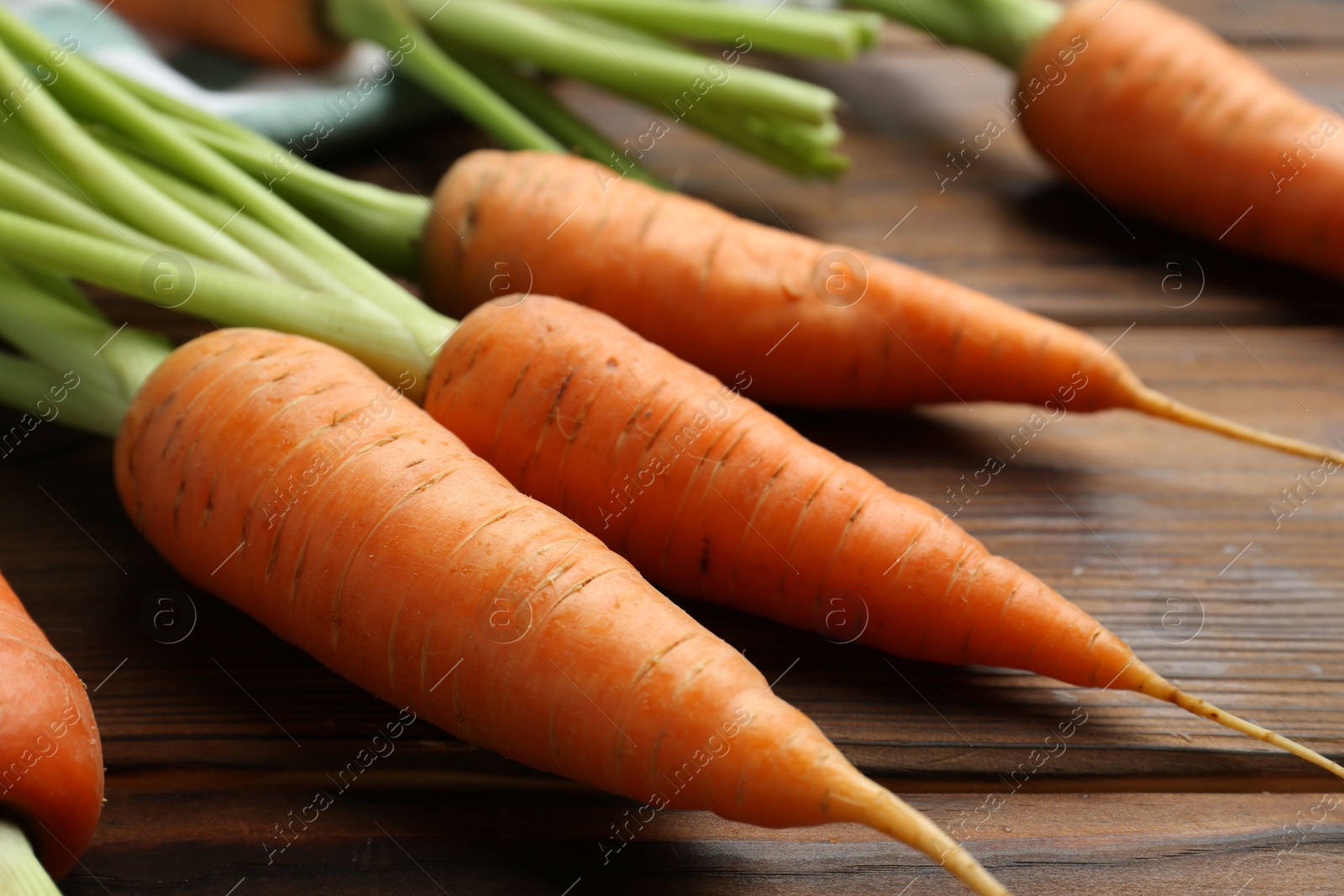 Photo of Tasty ripe juicy carrots on wooden table, closeup