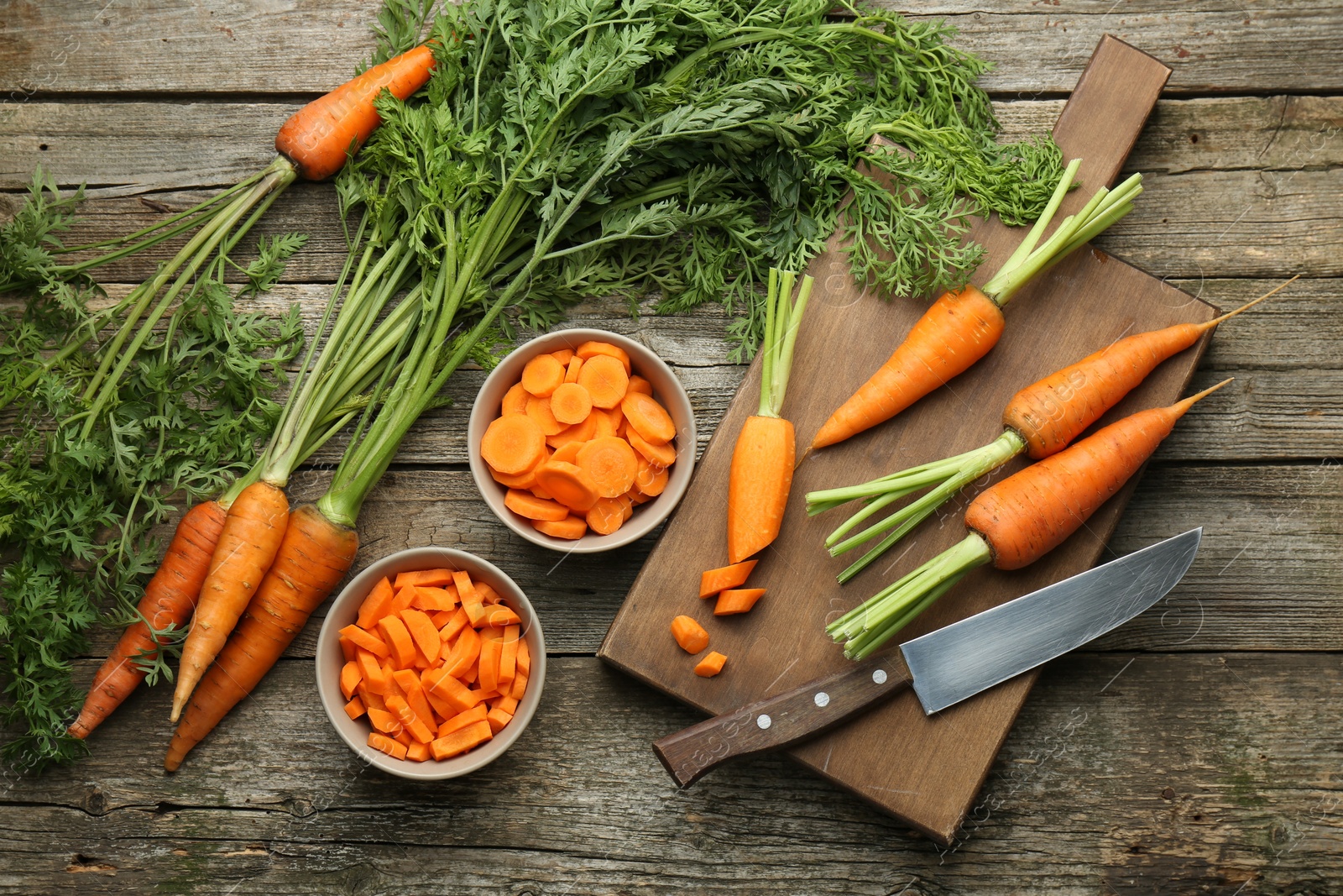 Photo of Fresh carrots and knife on wooden table, flat lay