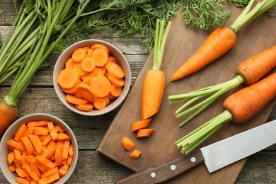 Photo of Fresh carrots and knife on wooden table, flat lay