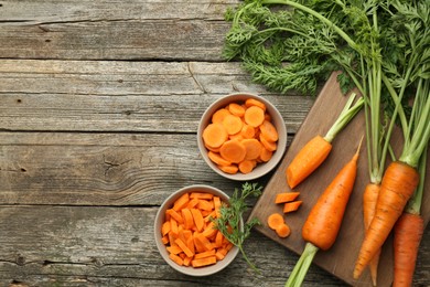 Photo of Whole and cut carrots on wooden table, flat lay. Space for text