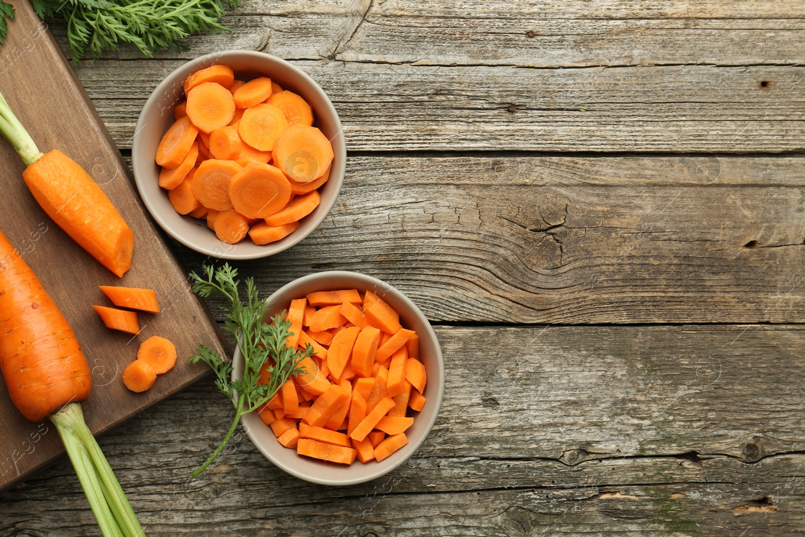 Photo of Whole and cut carrots on wooden table, flat lay. Space for text