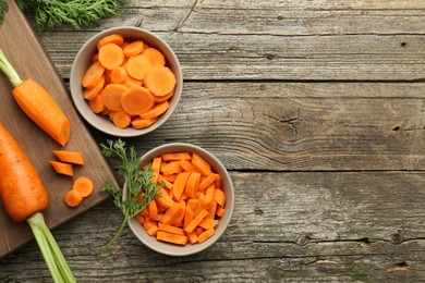 Whole and cut carrots on wooden table, flat lay. Space for text