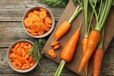 Whole and cut carrots on wooden table, flat lay