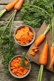 Whole and cut carrots on wooden table, flat lay