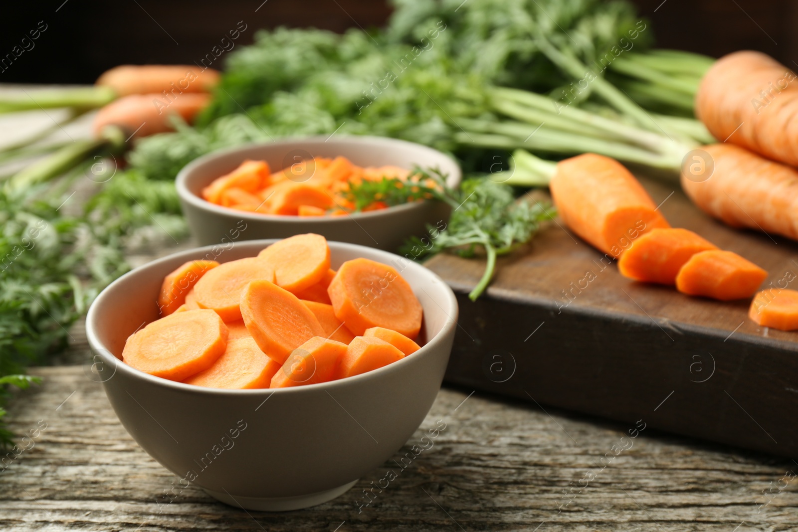 Photo of Cut carrot in bowl on wooden table, closeup