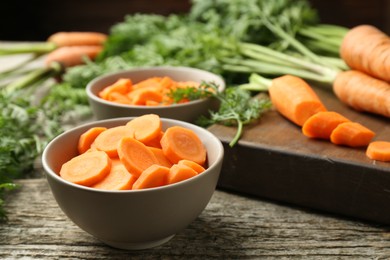 Photo of Cut carrot in bowl on wooden table, closeup