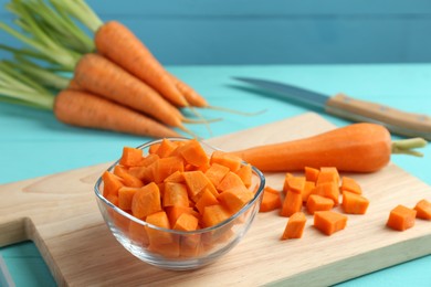 Photo of Delicious chopped carrot in bowl on light blue wooden table, closeup