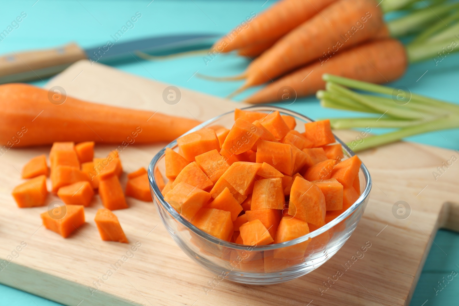 Photo of Delicious chopped carrot in bowl on light blue wooden table, closeup