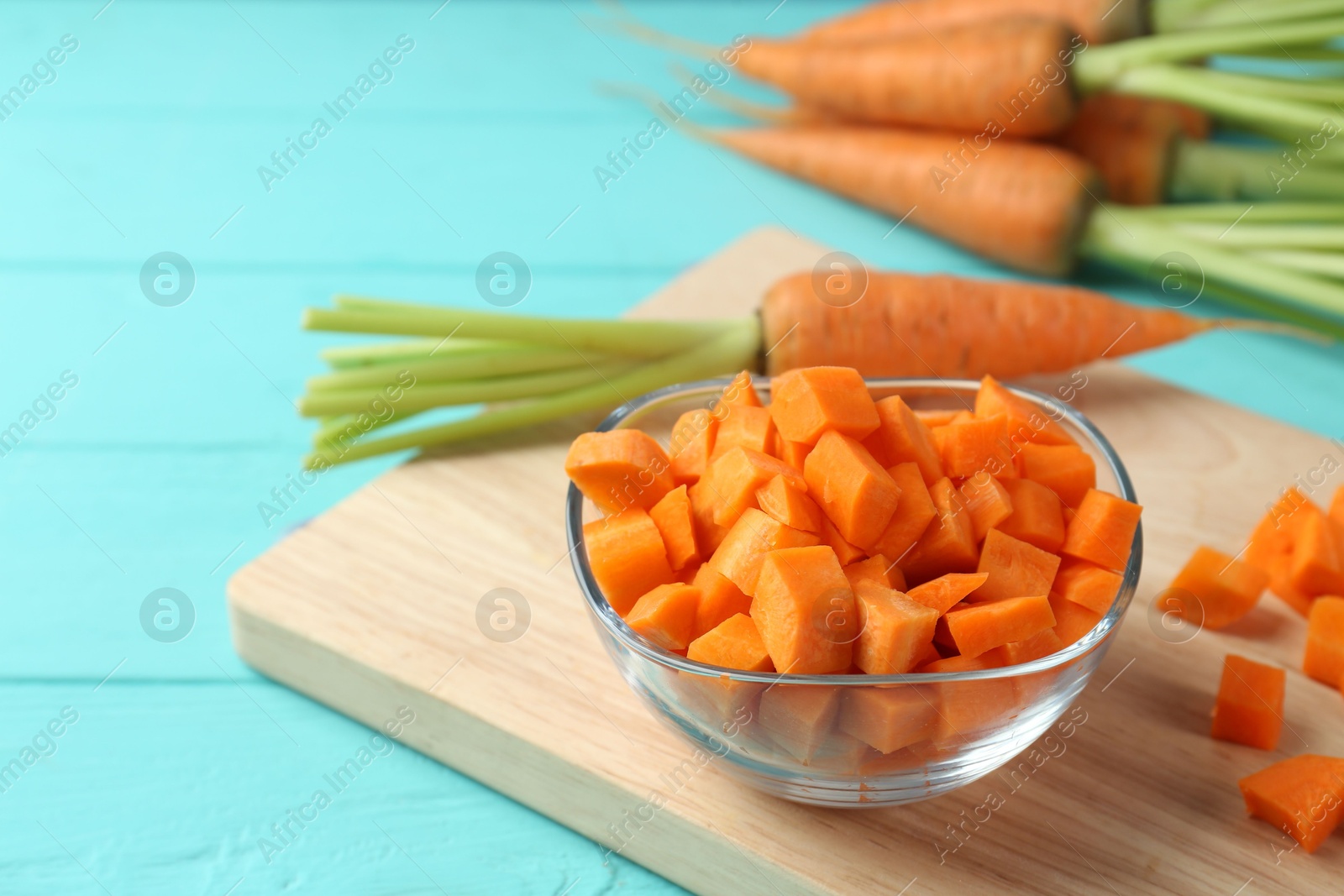 Photo of Delicious chopped carrot in bowl on light blue wooden table, closeup