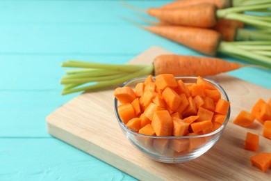 Photo of Delicious chopped carrot in bowl on light blue wooden table, closeup