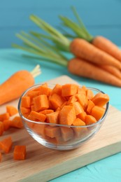 Photo of Delicious chopped carrot in bowl on light blue wooden table, closeup