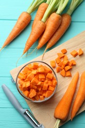 Chopped carrot in bowl, fresh vegetables and peeler on light blue wooden table, flat lay