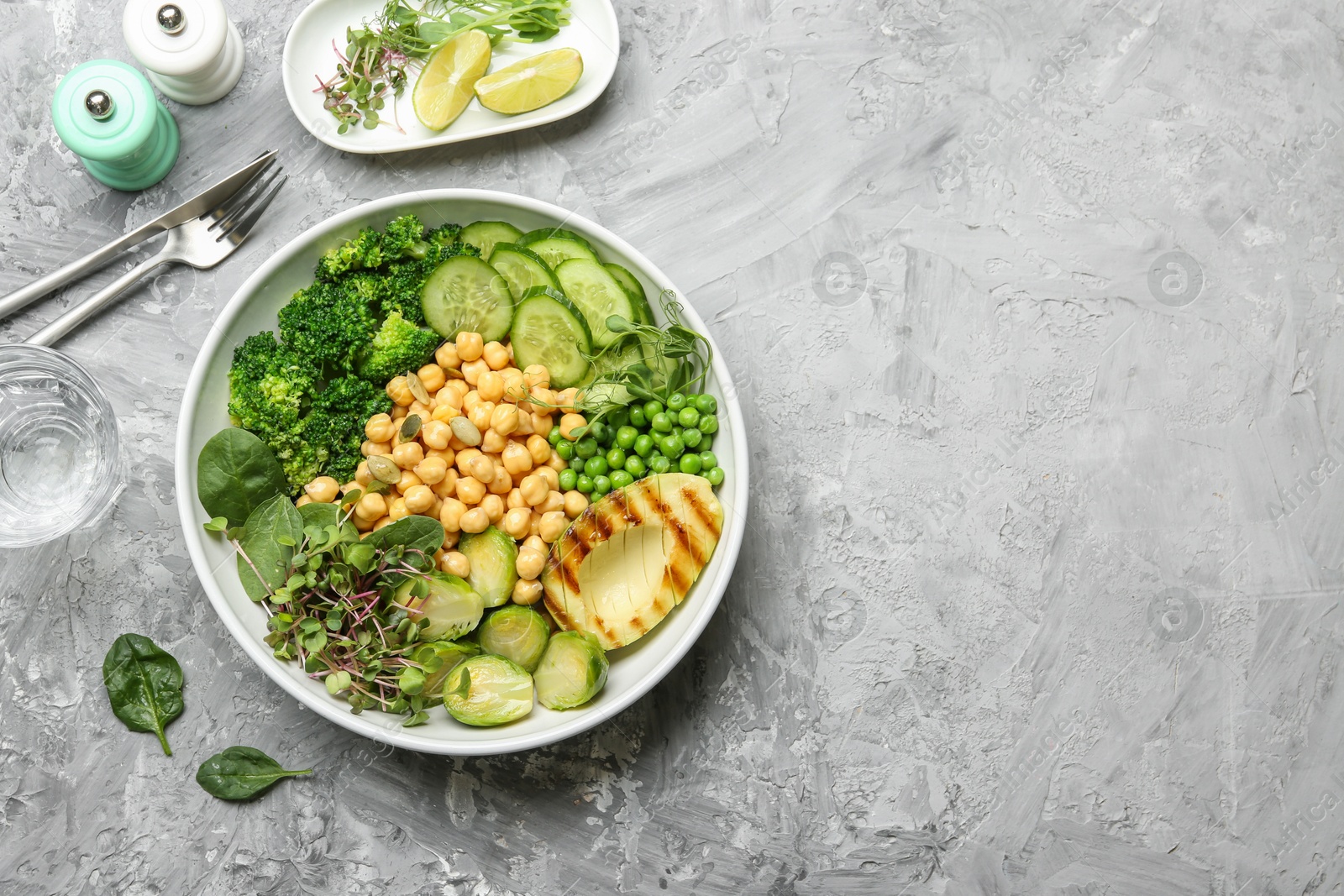 Photo of Healthy meal. Tasty vegetables and chickpeas in bowl on grey table, flat lay. Space for text