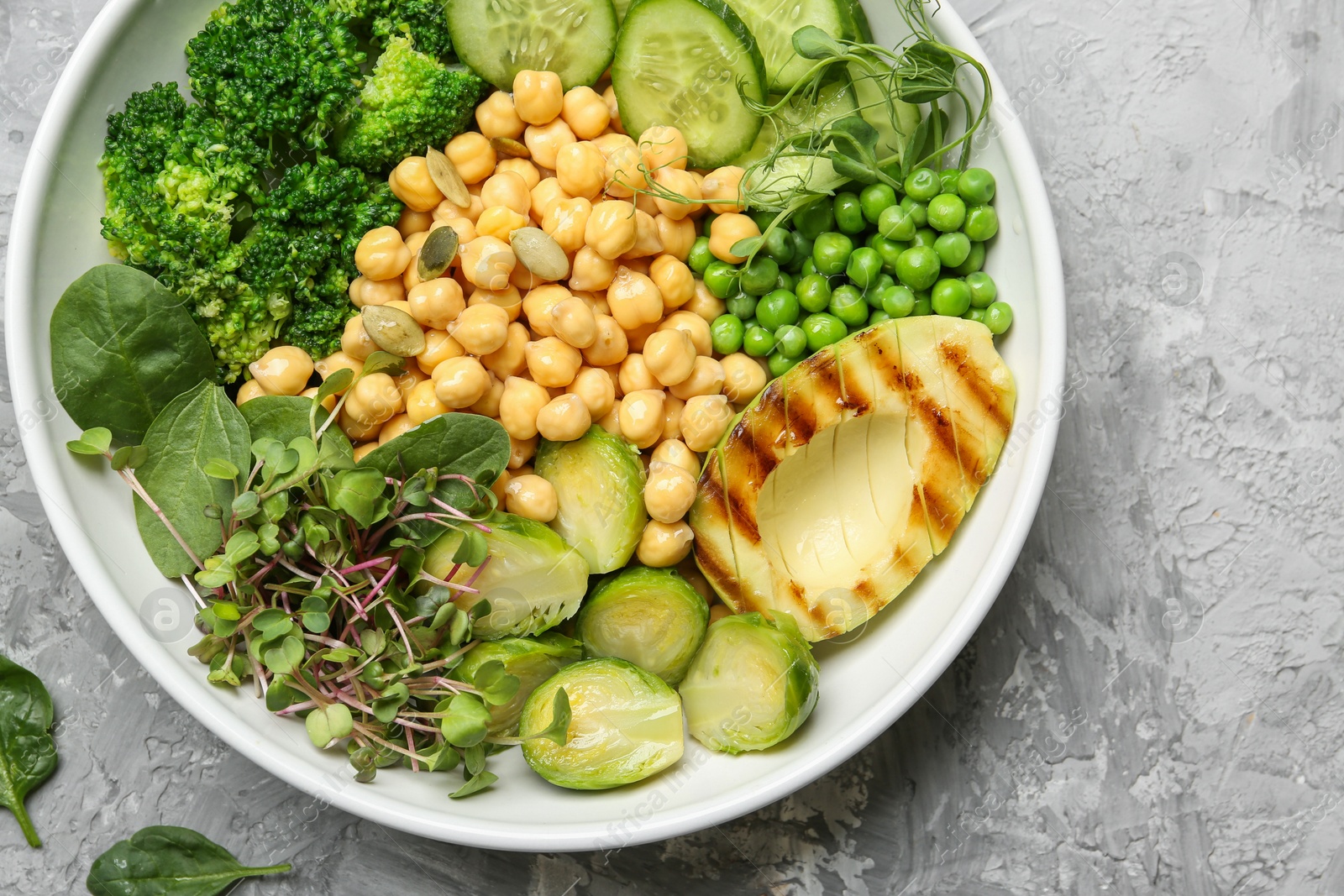 Photo of Healthy meal. Tasty vegetables and chickpeas in bowl on grey table, top view