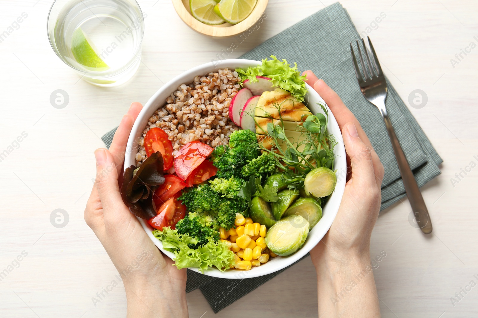 Photo of Healthy meal. Woman with bowl of tasty products at white table, top view