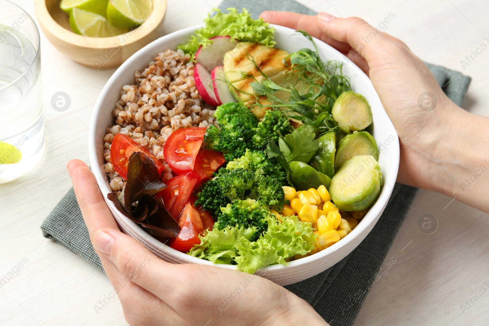 Photo of Healthy meal. Woman with bowl of tasty products at white table, closeup