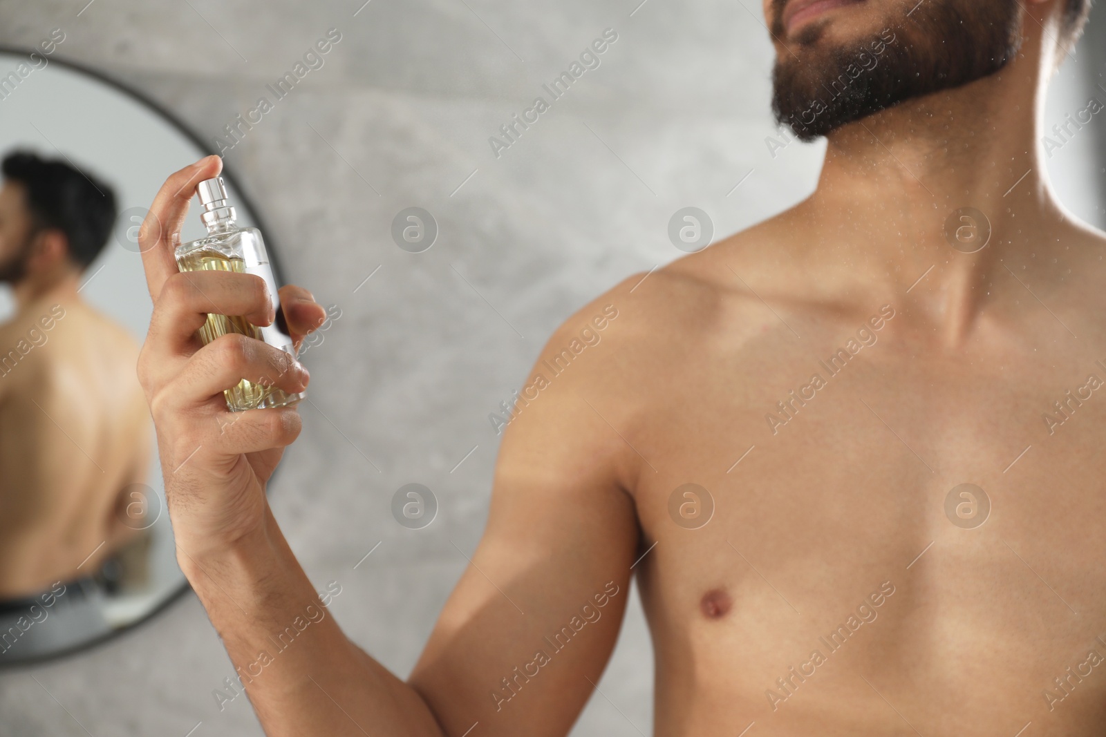 Photo of Young man spraying luxury perfume indoors, closeup