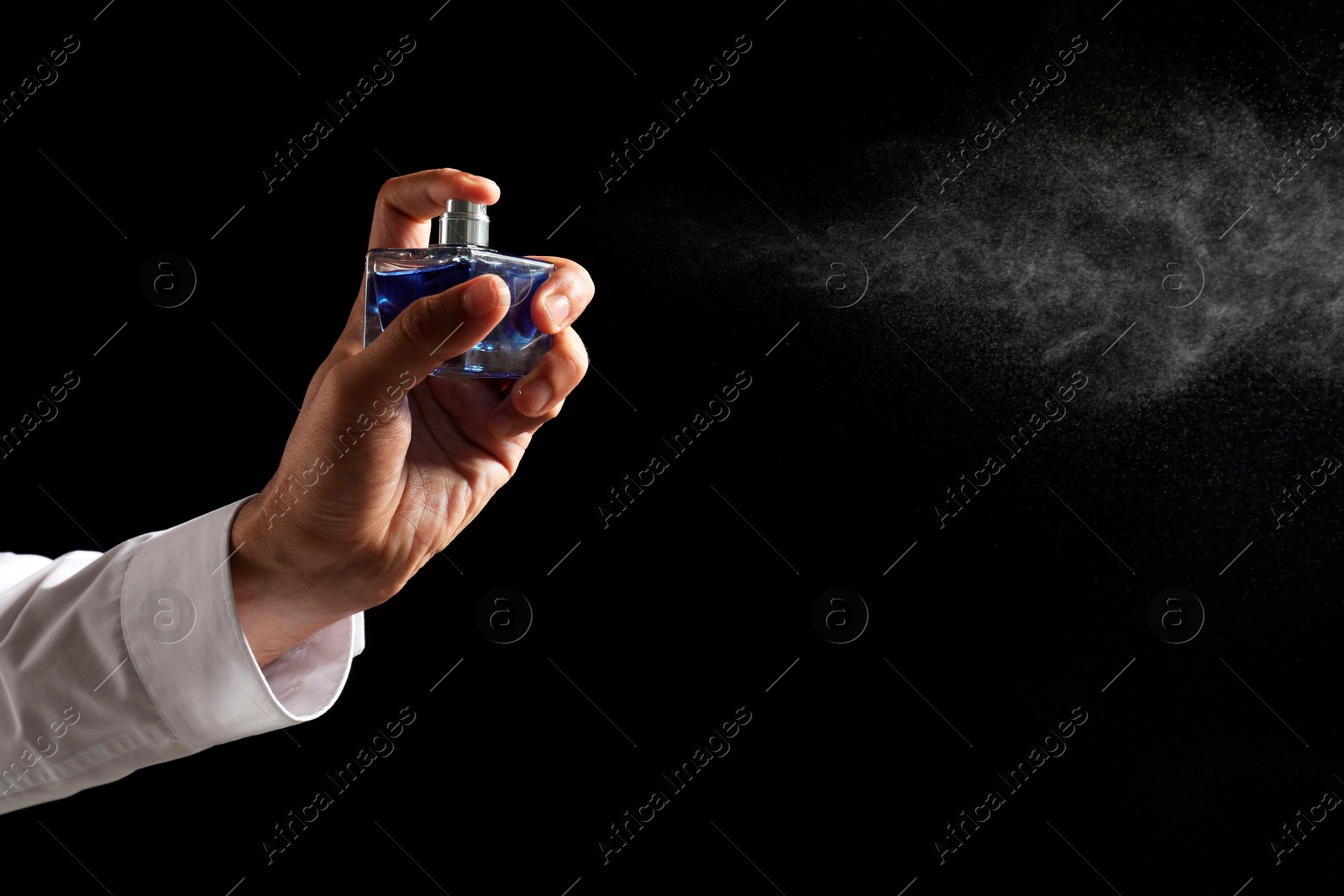 Photo of Man spraying luxury perfume on dark background, closeup. Space for text