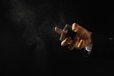 Man spraying luxury perfume on dark background, closeup. Space for text