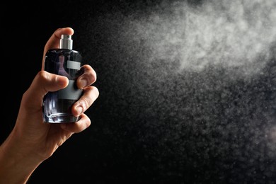 Photo of Man spraying luxury perfume on dark background, closeup. Space for text