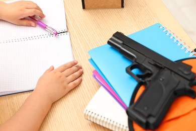 Child at desk with school stationery and gun, closeup