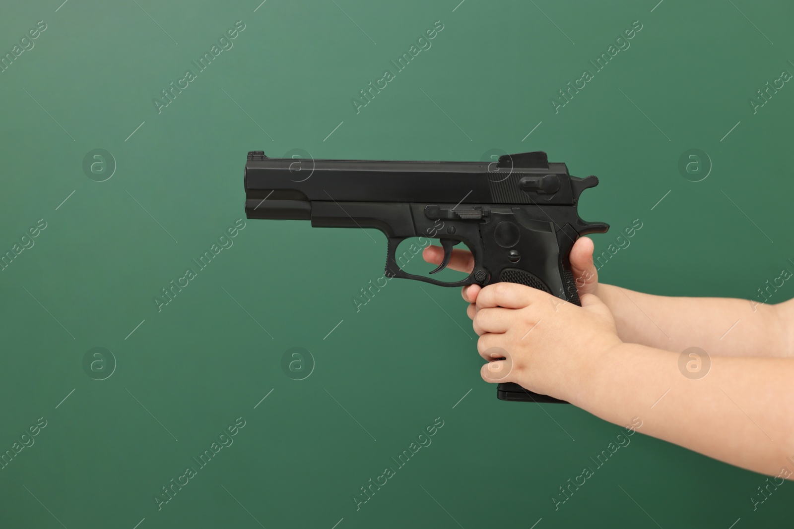 Photo of Child with gun against chalkboard, closeup. School shooting