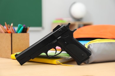 Photo of School stationery and gun on desk in classroom, closeup