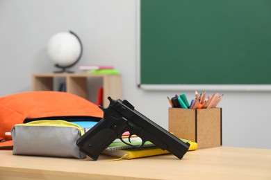 Photo of School stationery and gun on desk in classroom