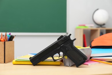 Photo of School stationery and gun on desk in classroom