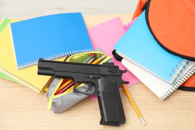 Photo of School stationery and gun on wooden desk, closeup