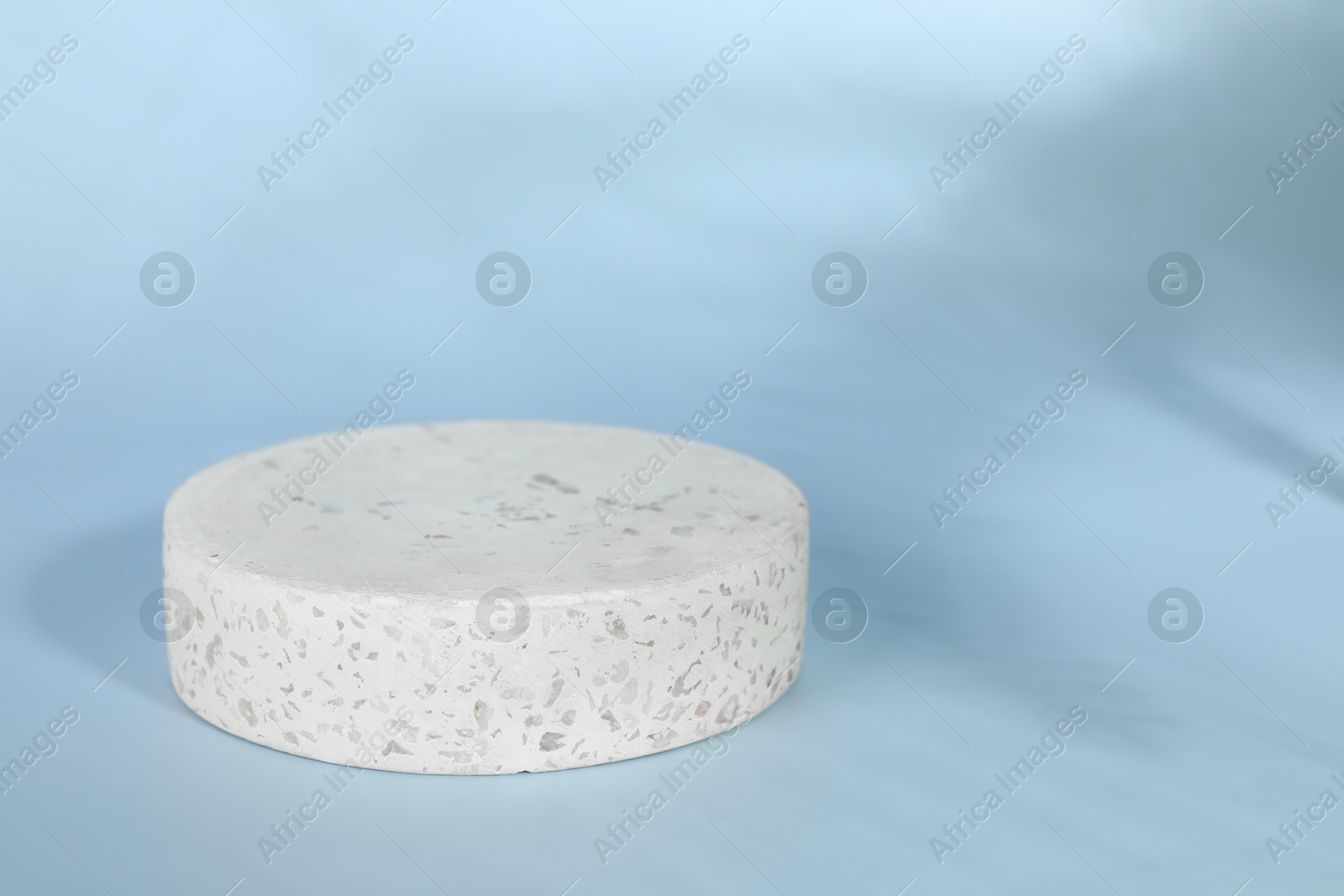 Photo of Presentation of product. Round podium and shadows on light blue background. Space for text