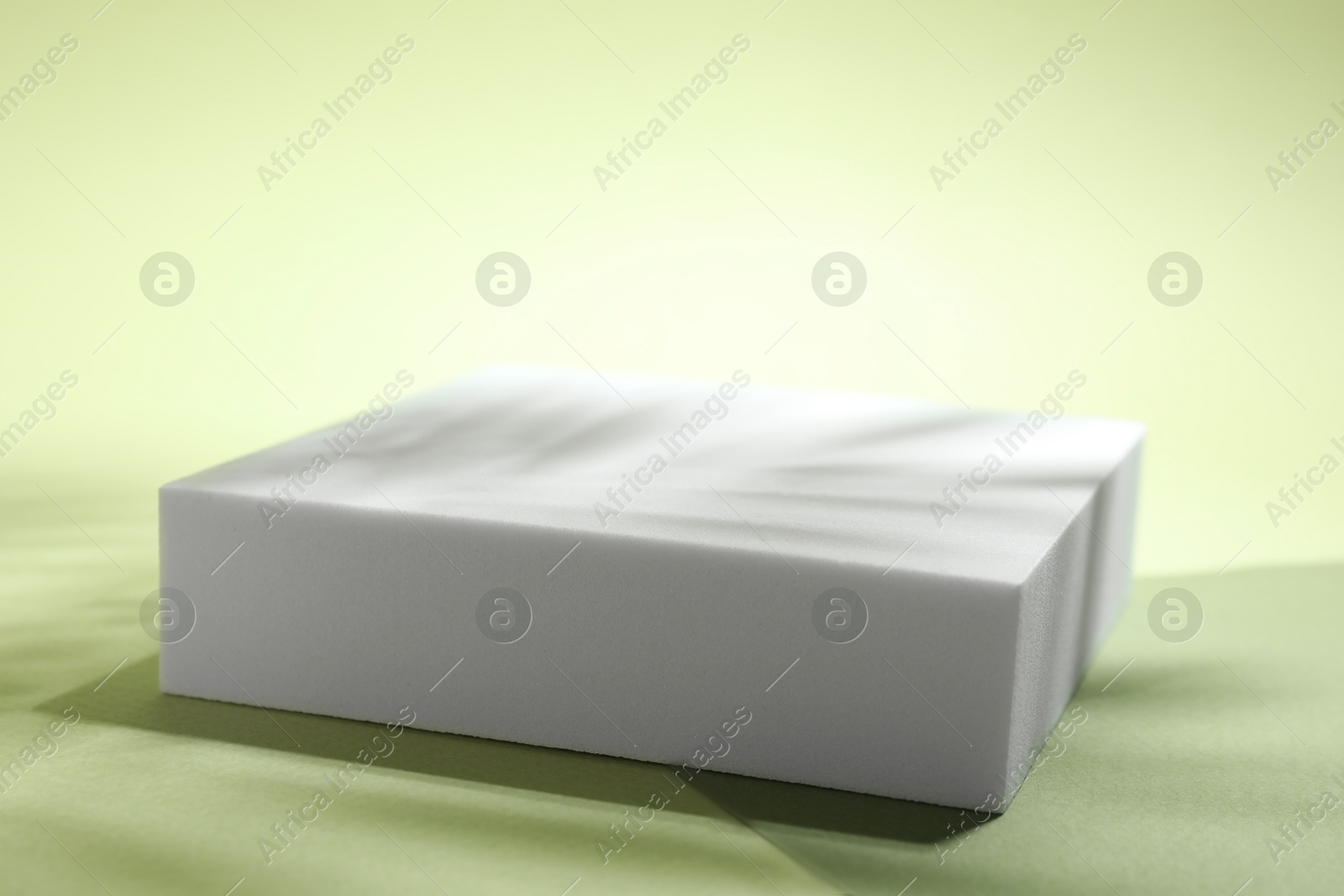 Photo of Presentation of product. Podium, paper and shadows on light green background. Space for text\