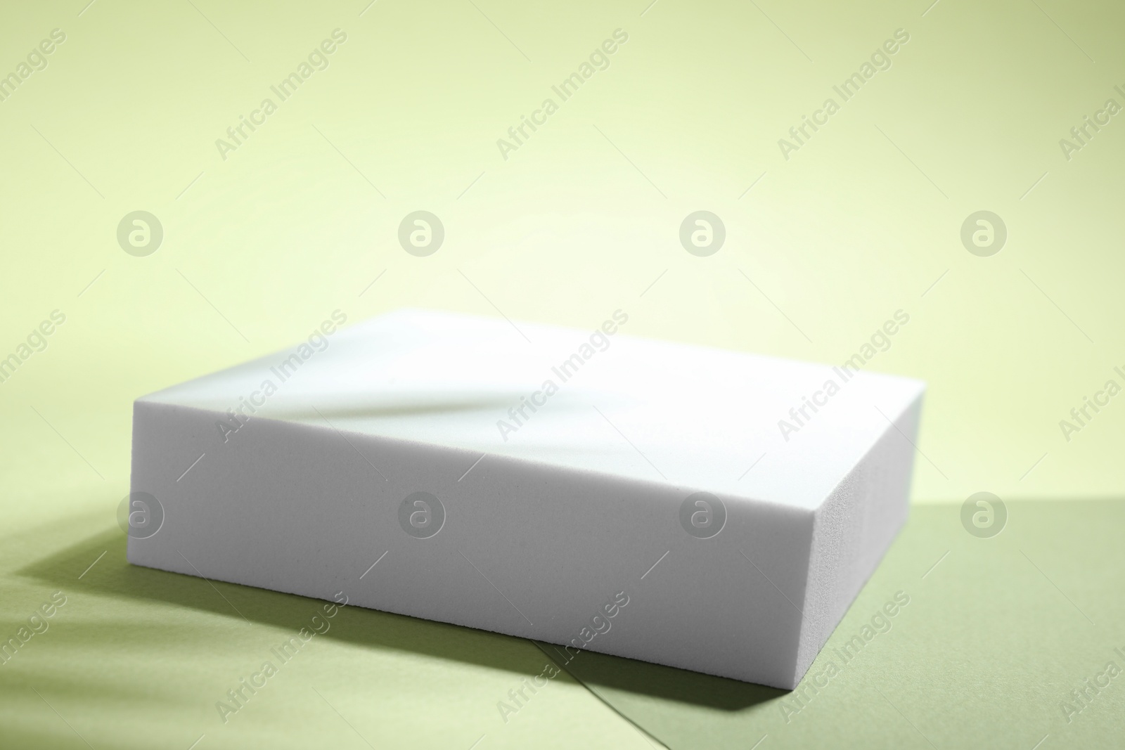 Photo of Presentation of product. Podium, paper and shadows on light green background. Space for text\