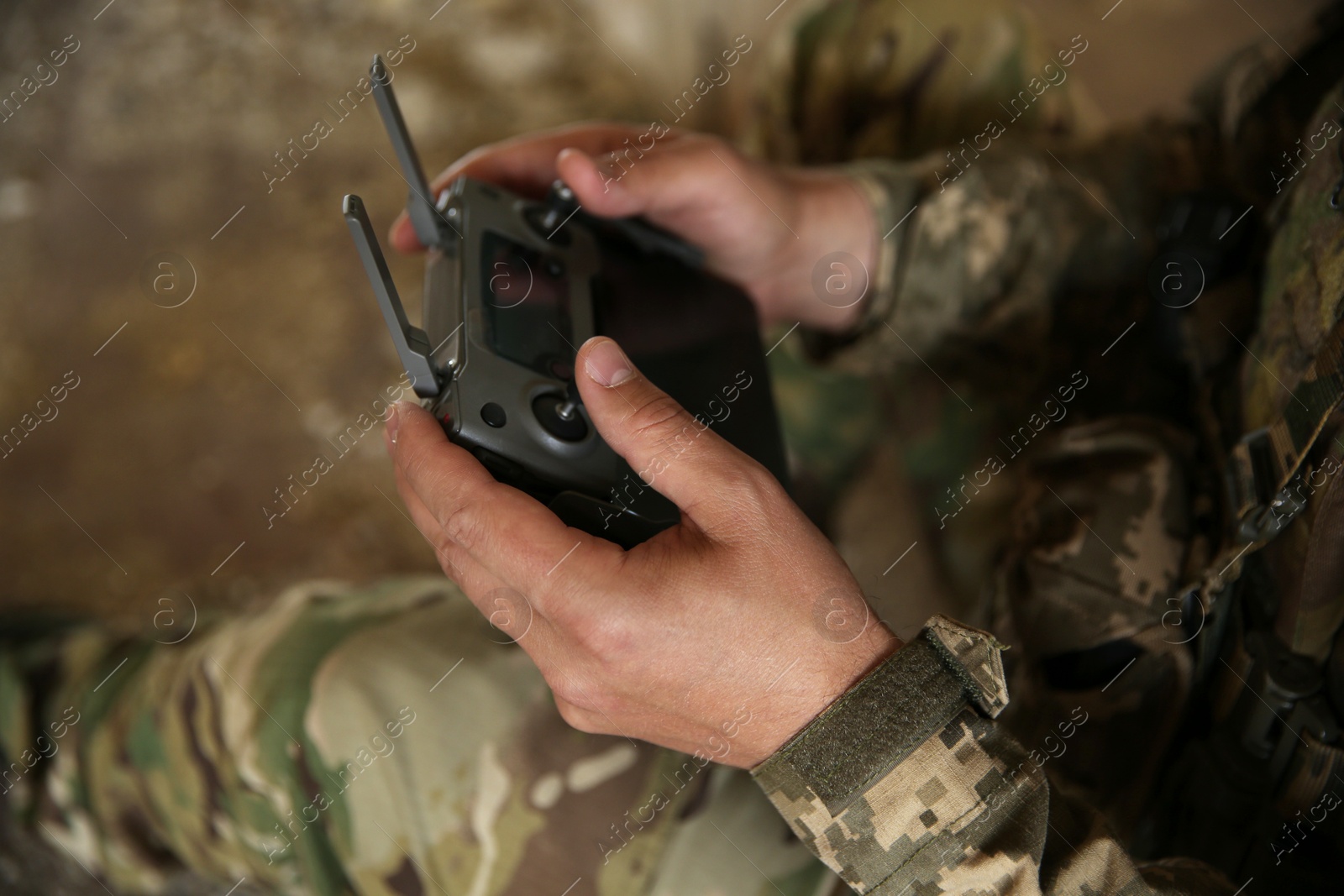 Photo of Military mission. Soldier in uniform with drone controller inside abandoned building, closeup