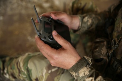Military mission. Soldier in uniform with drone controller inside abandoned building, closeup