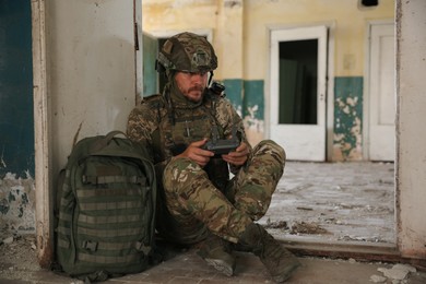 Military mission. Soldier in uniform with drone controller inside abandoned building