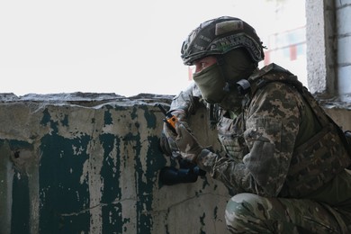 Military mission. Soldier in uniform with radio transmitter inside abandoned building, space for text