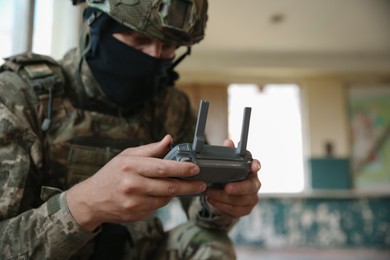 Military mission. Soldier in uniform with drone controller inside abandoned building, selective focus. Space for text