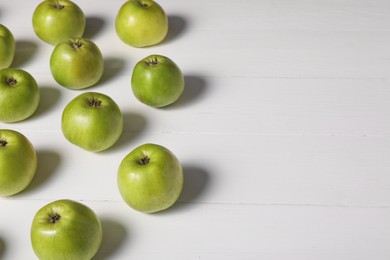 Photo of Fresh ripe green apples on white wooden table. Space for text