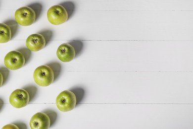 Fresh ripe green apples on white wooden table, flat lay. Space for text