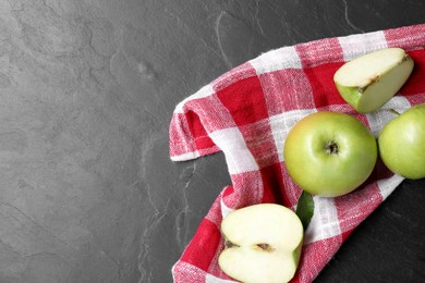 Photo of Whole and cut green apples on dark grey table, flat lay. Space for text