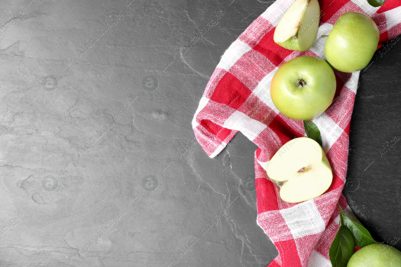 Photo of Whole and cut green apples on dark grey table, flat lay. Space for text