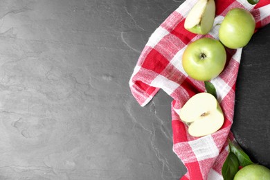 Photo of Whole and cut green apples on dark grey table, flat lay. Space for text